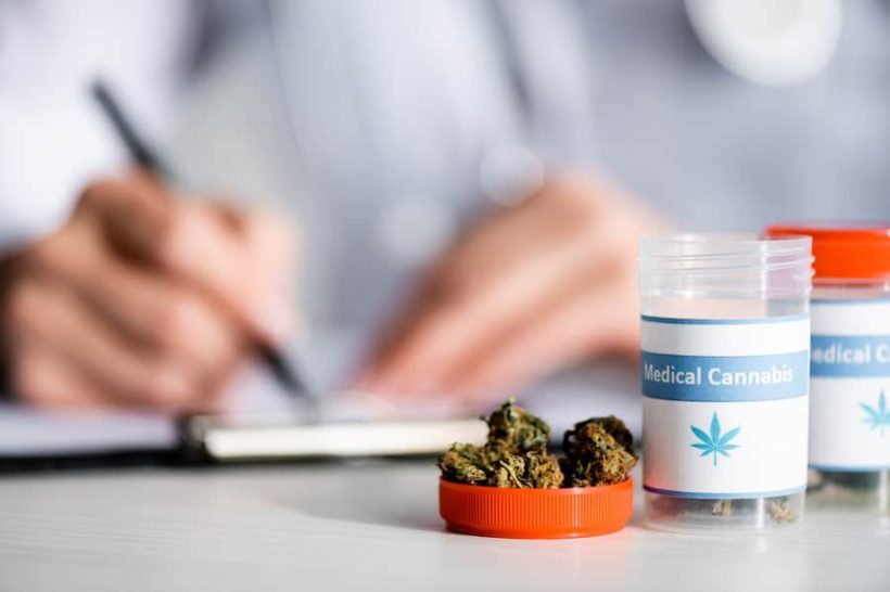 Selective focus of dried weed and bottles with medical cannabis lettering near doctor writing prescription