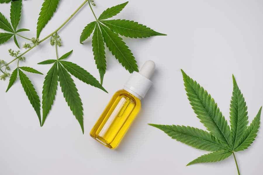 Cannabis oil and hemp leaf on white background, flat lay. Hemp CBD oil for skin care. — Photo